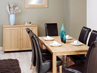 shallow focus photography of brown wooden dining table with six black leather padded chairs set inside house