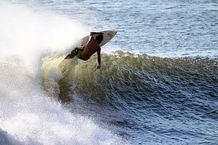 man in blue and black pants surfing on body of water