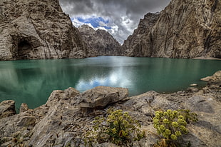 green water lake surrounded by gray mountain ranges photo shot during daytime HD wallpaper