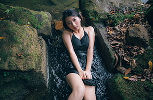 woman in black dress sitting on rock