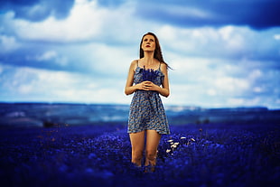 woman in dress standing on middle of flower fields looking up