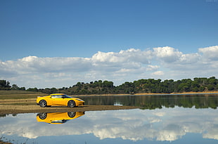 yellow sports car parked by beside body of water during daytime