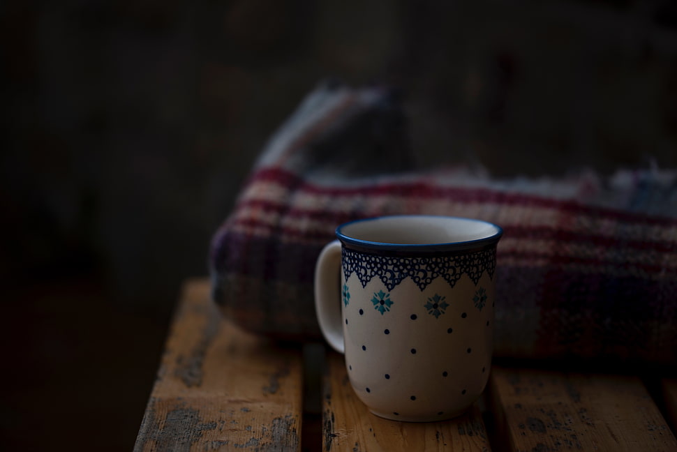 white and blue ceramic teacup behind multicolored textile HD wallpaper