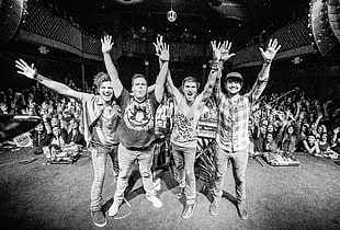 grayscale photo of people raising hands on stage