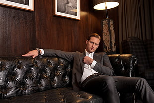 man in dress suit sitting on sofa