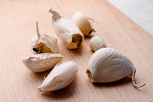six cloves of garlic on brown wooden table HD wallpaper