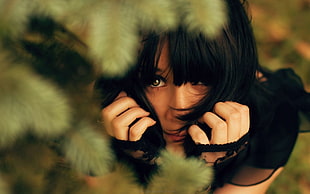 woman in black shirt hiding on green tree