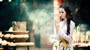 female holding stick while praying facing jar
