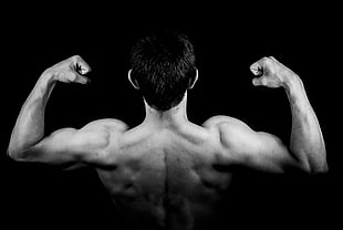 grayscale photo of man flexing biceps in back view