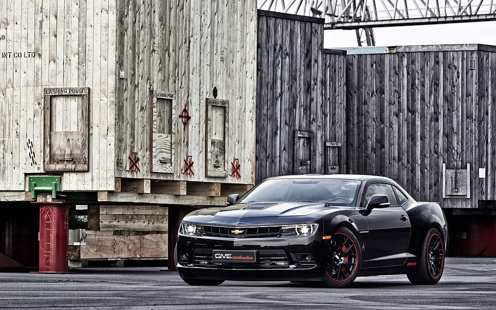 black Chevrolet Camaro Z-series coupe parked near brown wooden building at daytime HD wallpaper
