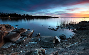 landscape photograph of rocks at lakeside during golden hour