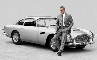 Daniel Craig leaning on classic silver Aston Martin