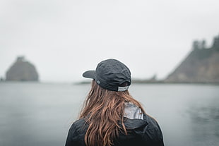 person wearing black cap near body of water photo