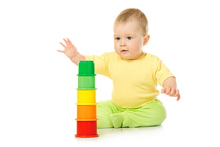 baby's yellow shirt and green pants playing plastic toy HD wallpaper