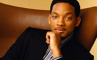 Will Smith in black formal coat sitting on leather chair
