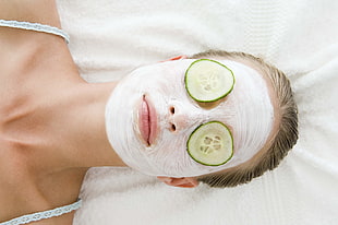 woman with face cream and two cucumbers