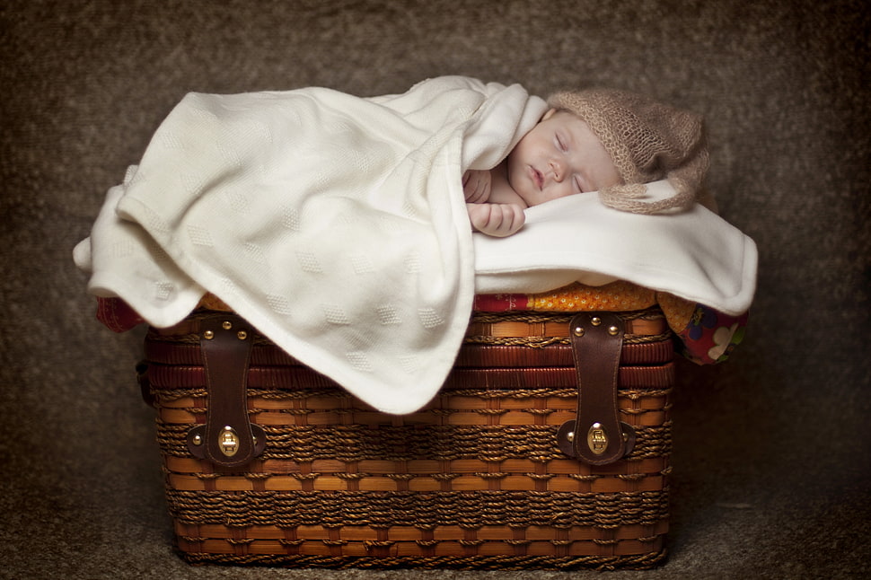 baby lying on white comforter over brown basket HD wallpaper