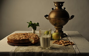 brass-colored coffee urn beside baked cake on white table