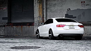 white Audi coupe parked near gray painted concrete wall
