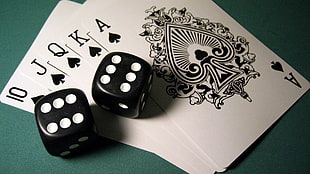 two black-and-white dice on top of spade royal straight flush cards