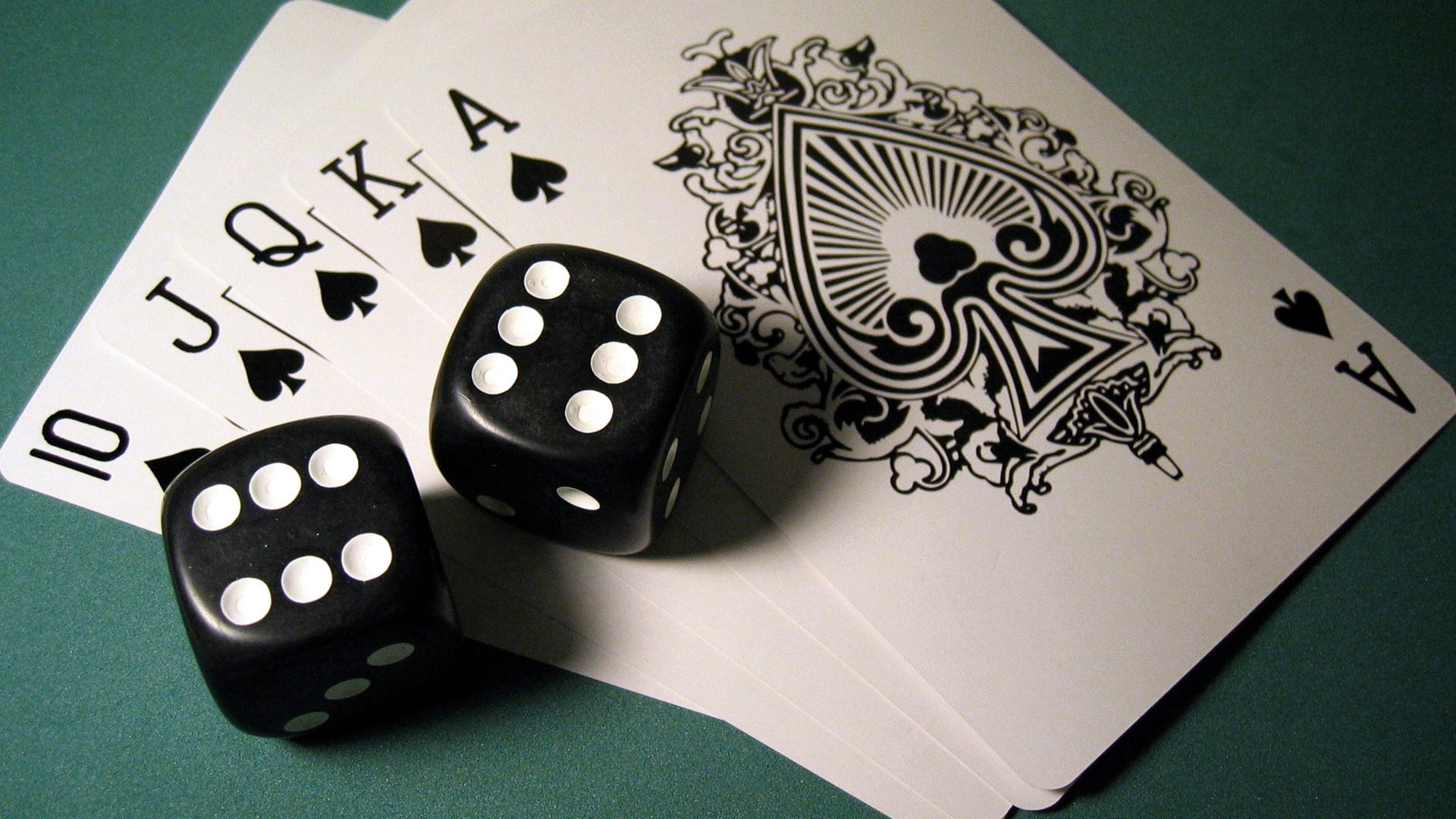 two black-and-white dice on top of spade royal straight flush cards