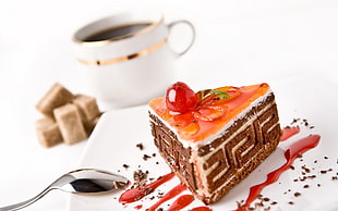 triangular-cut chocolate and vanilla cake with syrup and cherry topping beside black-liquid filled white ceramic cup