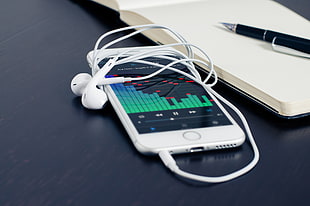 silver iPhone 6 with EarPods beside notebook