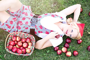 woman holding apple lying on a grass field