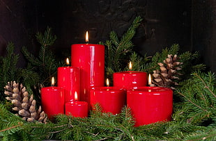 red candles and brown pine cone with garland