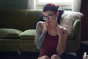 woman wearing maroon tank top and black eyeglasses near sofa