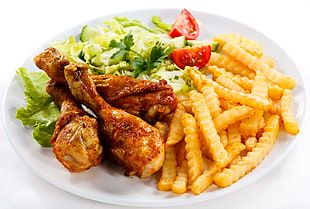 three fried chicken with french fries and vegetables both on round white ceramic plate