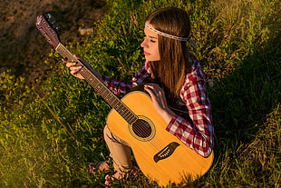 woman in red and white checked long sleeved shirt with acoustic guitar