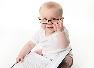 baby in white shirt holding black eyeglasses