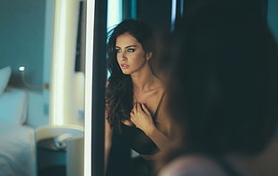 woman wearing black brassiere in front of mirror in room