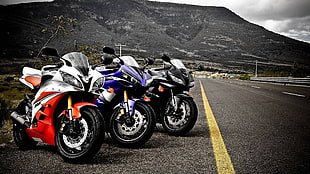 three assorted sports bike parked at the side of asphalt road