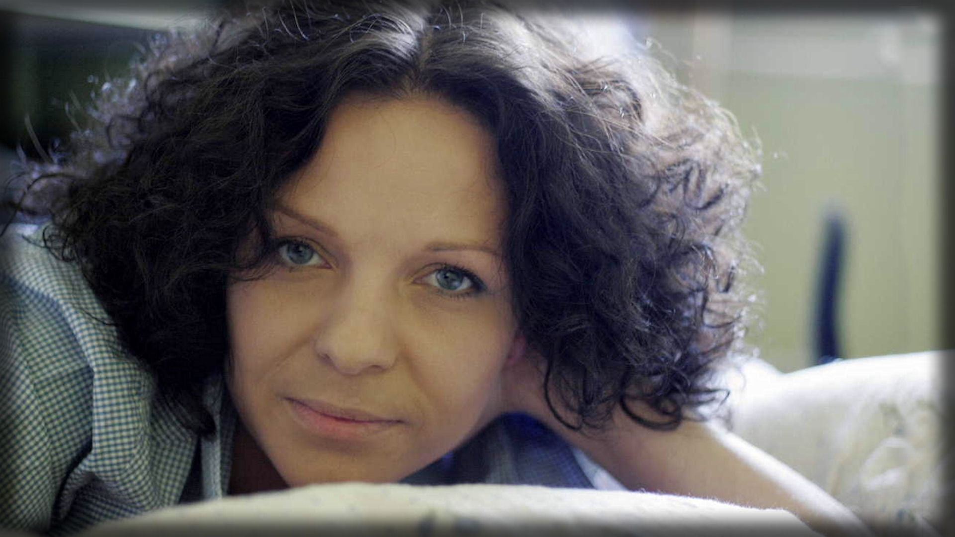 woman in gray shirt lying on white textile