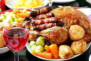cooked whole chicken with appetizers and clear glass wine bottle with red wine