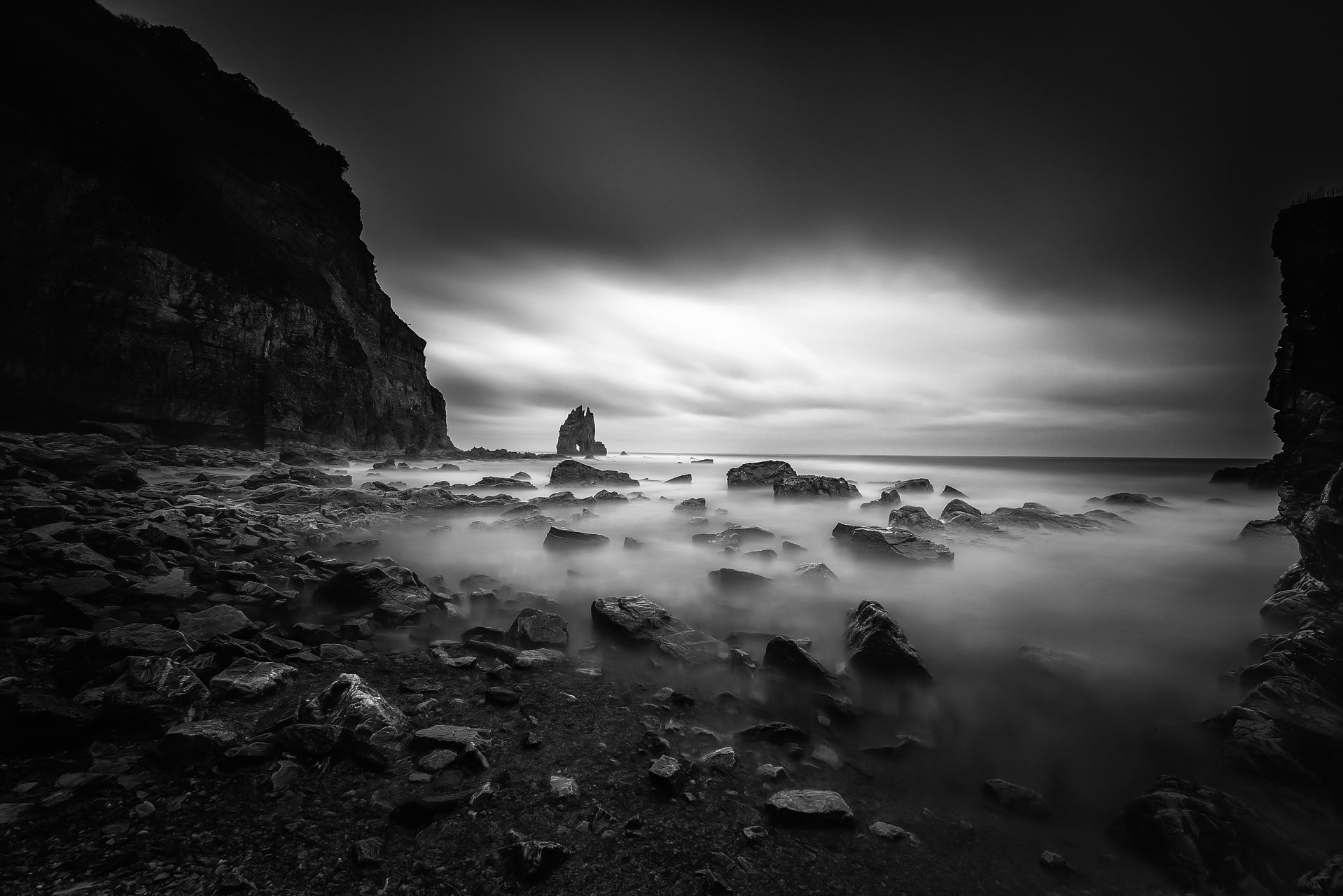 grayscale photo of rocks covered in fog