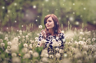 smiling woman holding a white dandelion during daytime