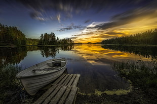 white boat beside brown wooden dock in body of water in timelapse photography
