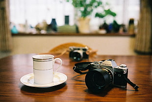 black DSLR camera with white ceramic cup