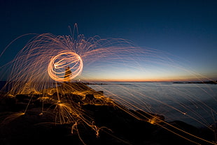 time-lapse photograph of person holding firecrackers near sea shore