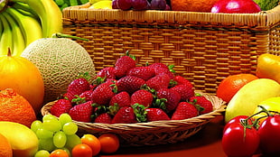 strawberries on brown wicker bowl surrounded with variety of fruits