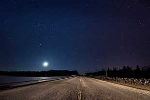 road beside the body of water during nighttime HD wallpaper