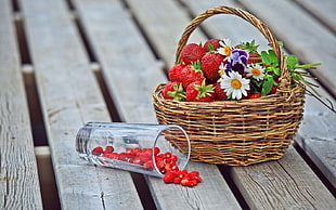 photography of strawberries on brown wicker basket beside clear drinking glass during day time