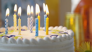 shallow photograph of lighted colored birthday candles on the cake