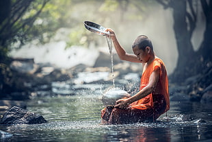 selective focus photography of monk in river dripping water on stainless steel container
