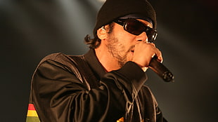 man in black jacket and sunglasses holding microphone