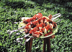 depth of field of skewers on green vegetable leaf and white plate during day time
