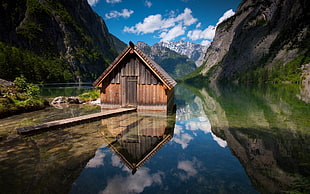 brown shed between body of water near moutains HD wallpaper